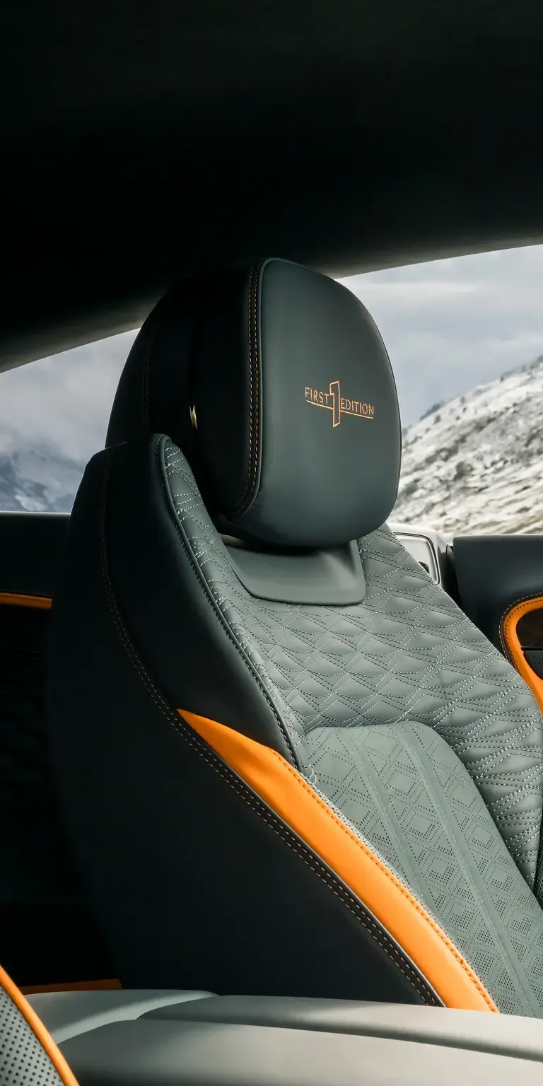 Close-up of quilted leather front seat with “First Edition” embroidery and orange accents inside a Bentley Continental GT.